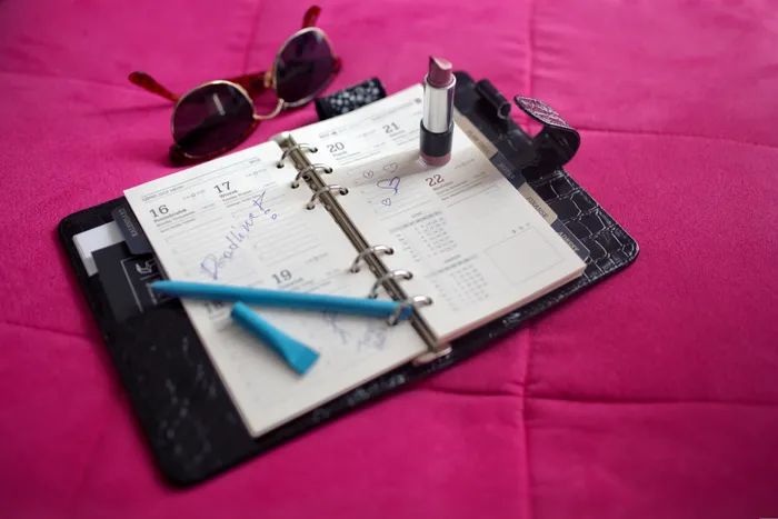 Photo of an old-school organizer with some personal items, like lipstick and sunglasses.